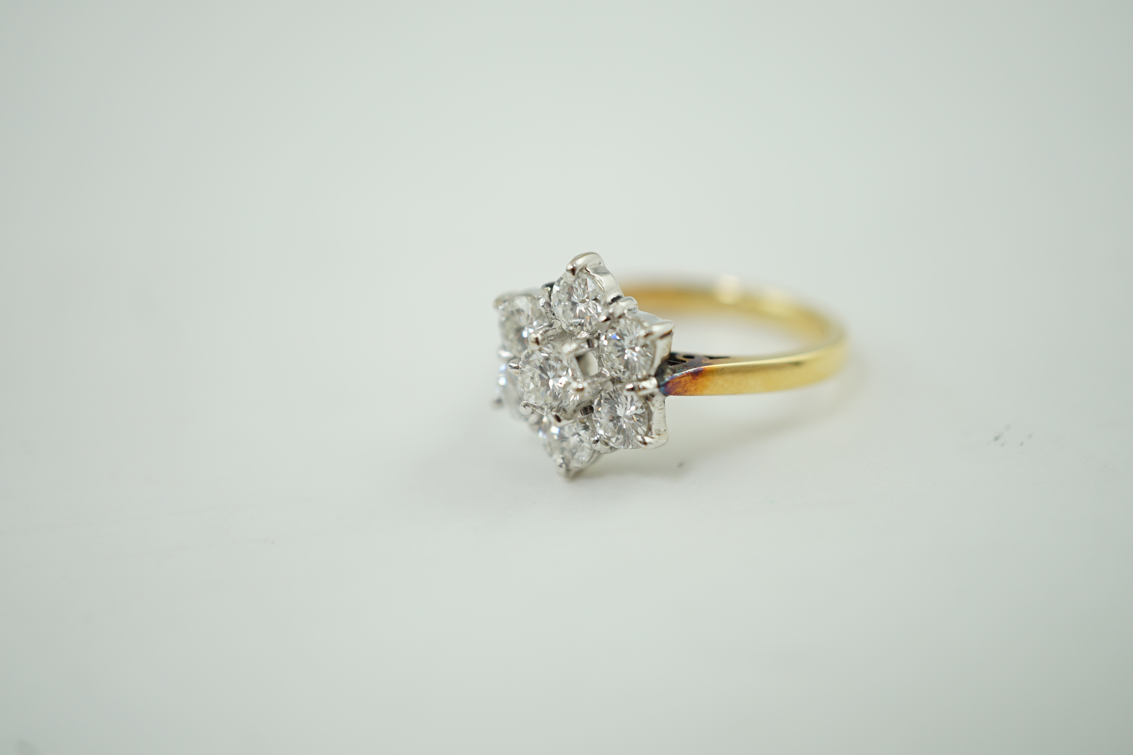 A modern 18ct gold and seven stone diamond set flower head cluster ring